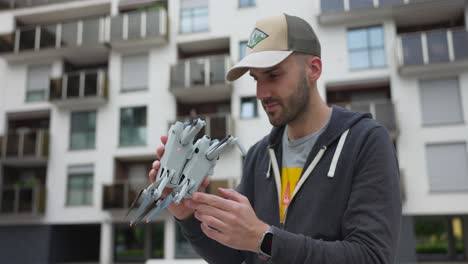 Caucasian-man-compares-two-drones-he-holds-in-his-hands,-DJI-Mini-4-Pro