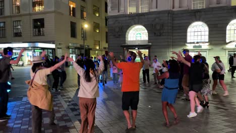 A-large-group-of-happy-people-dance-in-a-circle-around-a-dancer-wearing-a-light-suit-at-a-street-festival-in-Te-Komititanga-Plaza-in-Queensstreet-in-New-Zealand