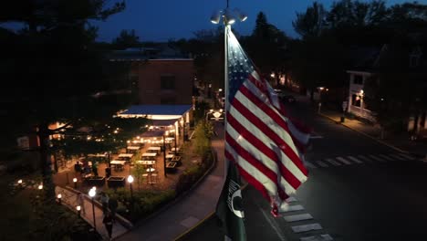 Aerial-orbit-shbot-of-lighting-american-flag-in-small-town-at-night