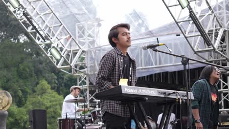 Asian-Young-Man-Playing-Keyboard-On-Outdoor-Stage-With-Band-During-Music-Festival