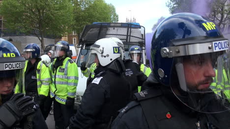 Officers-from-the-Metropolitan-Territorial-Support-Group-wearing-Nato-helmets-form-a-cordon-in-front-of-a-police-van-as-purple-smoke-from-flare-rises-into-the-air-during-scenes-of-unrest