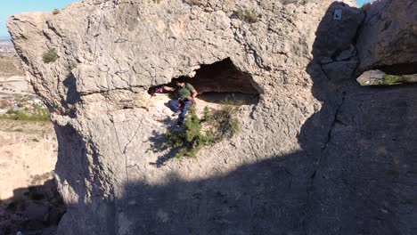 Sportsmen-rock-climbing-aerial-view-of-sportsman-rapelling-mountain-in-La-Panocha,-el-Valle-Murcia,-Spain-woman-rapel-down-a-mountain-climbing-a-big-rock