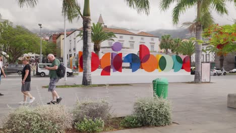 People-walk-near-colorful-Madeira-Sign-with-stylized-letters-at-Funchal-city