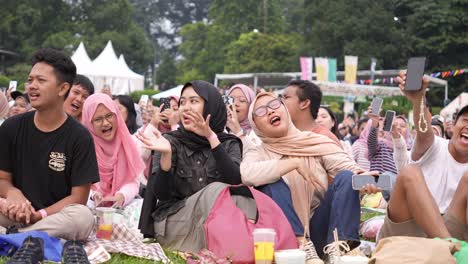 Pueblo-Indonesio-Cantando-Divirtiéndose-Y-Sentado-En-El-Suelo-En-Un-Concierto-Al-Aire-Libre.