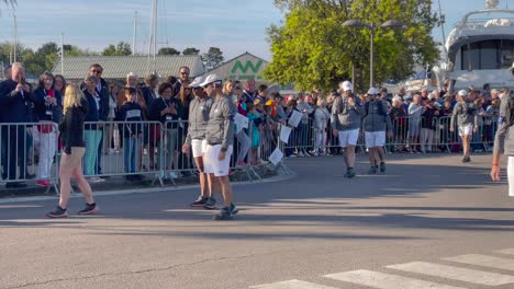 Blonde-woman-shows-the-Olympic-flame-to-the-street-crowd-while-giving-instruction-to-security-staff-and-walking