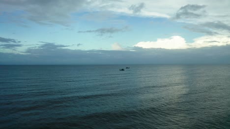 A-couple-of-boats-are-going-in-the-middle-of-the-water,-waves-are-visible-in-the-water