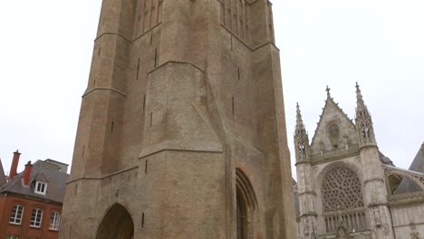 Medieval-belfry-and-Gothic-cathedral-in-Dunkirk,-France-on-an-overcast-day,-wide-shot