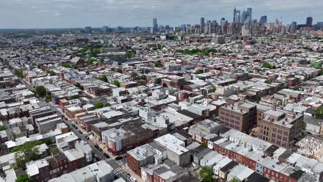 Luftaufnahme-Eines-Stadtteils-Von-Philadelphia-Mit-Reihen-Von-Wohnhäusern-Und-Der-Skyline-Der-Stadt-Im-Hintergrund