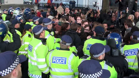 Metropolitan-and-City-of-London-police-officers-in-yellow-luminous-jackets,-some-in-Nato-riot-helmets,-push-back-a-crowd-of-resistant-protesters-during-a-public-order-situation