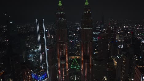 Aerial-view-away-from-the-illuminated-Petronas-Twin-Towers,-night-in-Kuala-Lumpur