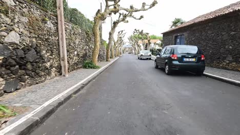 Driving-through-a-quaint-street-in-São-Miguel-with-pedestrians-on-the-sidewalk