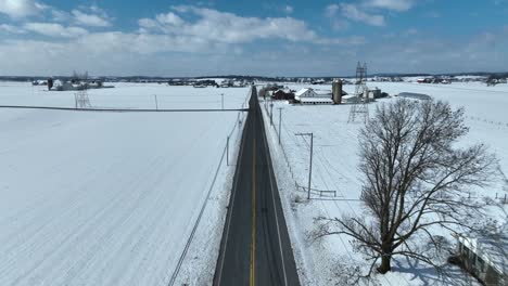 Snowy-winter-landscape-with-straight-street-in-rural-farm-area-in-USA