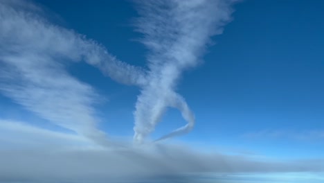 Aerial-view-of-some-white-contrails-crossing-a-blue-sky-shot-from-a-jet-flying-bellow-them