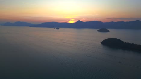 Tranquil-sunrise-with-radiant-beams-reflecting-off-the-calm-sea,-creating-a-picturesque-silhouette-of-islands-against-the-morning-sky