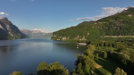 Aerial-footage-of-Walensee,-showcasing-clear-lake-waters,-verdant-hills,-and-surrounding-alpine-mountains