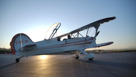 Aerobatic-Biplane-on-the-Ground-with-Open-Canopy,-Sunshine-from-Behind