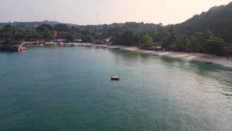 Morning-mood-Lovely-aerial-view-flight-of-a-tropical-island-with-a-long-wooden-pier-leading-to-a-floating-restaurant,-surrounded-by-turquoise-waters-and-lush-green-rainforest