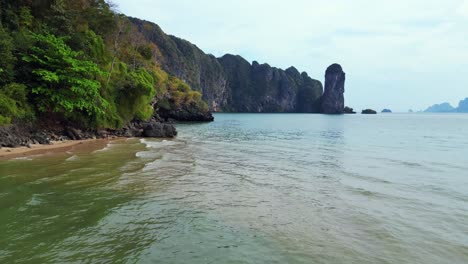 Breathtaking-view-of-a-secluded-bay-with-turquoise-water,-surrounded-by-towering-cliffs-covered-in-lush-green-vegetation