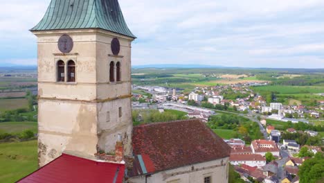 Old-castle-tower-and-township-in-horizon,-aerial-orbit-view