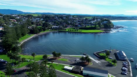 Landscape-drone-aerial-view-of-Kiama-harbour-carpark-blowhole-wharf-pier-bay-headland-with-residential-housing-suburbs-South-Coast-Australia-travel-tourism