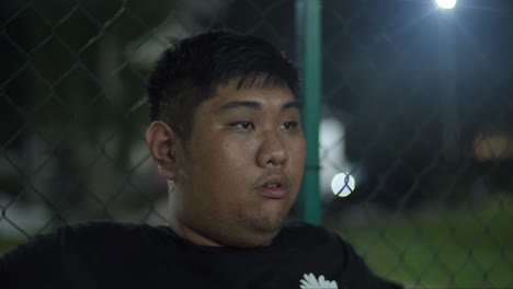 Overweight-Asian-man-on-an-outdoor-court-contemplating-weight-loss