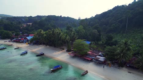 Morning-mood-Gorgeous-aerial-view-flight-speed-ramp-of-a-tropical-island-with-restaurant,-surrounded-by-turquoise-waters-and-lush-green-rainforest