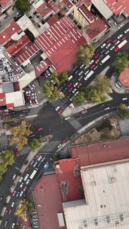 Slow-motion-aerial-view-of-a-bustling-avenue-with-busy-intersections-and-crosswalks,-CDMX,-vertical-mode