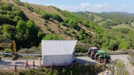 Aerial-View-Of-Tractor-Pulling-Mobile-House-Across-Road-In-Chiloe