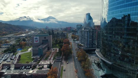 Aerial-Drone-Fly-American-Embassy-at-Santiago-de-Chile-Streets,-Skyscrapers-and-Andean-Cordillera-Hill-background