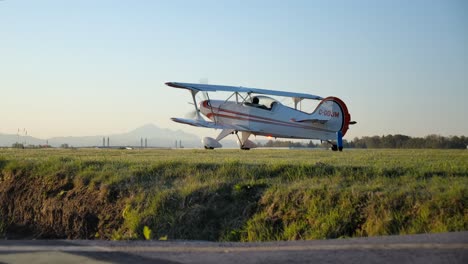 Low-Angle-Tracking-Shot-of-a-Vintage-Biplane-Taxiing-Out-To-the-Runway