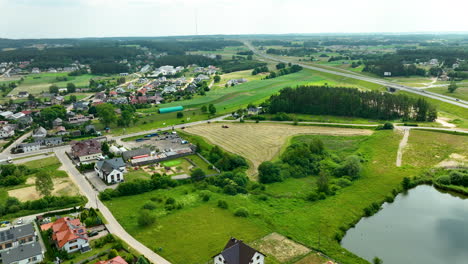 Aerial-view-of-a-suburban-area-featuring-a-mix-of-residential-houses,-fields,-and-a-small-pond