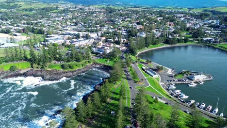 Aerial-drone-landscape-of-Kiama-main-town-rural-suburb-city-harbour-bay-foreshore-with-cars-on-street-housing-shops-residential-living-South-Coast-Gerringong-Australia