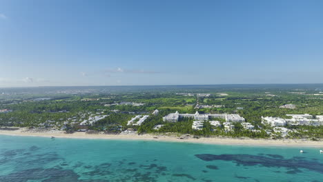 Schwenkende-Drohnenaufnahme-Von-Links-Nach-Rechts,-Die-Leicht-Nach-Oben-Zieht,-Um-Die-Bereiche-Jenseits-Des-Strandes-Eines-Beliebten-Touristenziels-In-Der-Dominikanischen-Republik-In-Der-Karibik-Zu-Zeigen