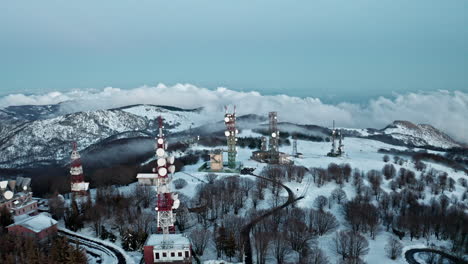 Verschneite-Landschaft-Mit-Mehreren-Funktürmen-Und-Bergblick-Im-Winter,-Luftaufnahme