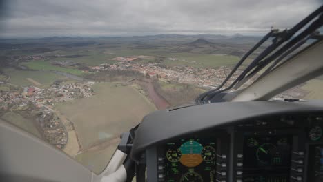 First-person-view-inside-the-cockpit-of-the-Bell-249-helicopter-as-it-flies-above-the-rural-landscape