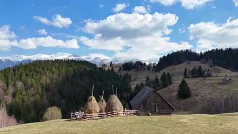 A-rustic-haystack-and-sheepfold-set-against-a-backdrop-of-rolling-hills-and-snowy-mountains