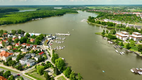 Aerial-view-of-a-tranquil-lakeside-Iława-town-with-boats-docked-at-marinas-and-lush-green-surroundings