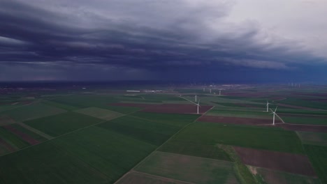 Windräder-Auf-Einer-Grünen-Wiese-Unter-Einem-Dunklen,-Stürmischen-Himmel