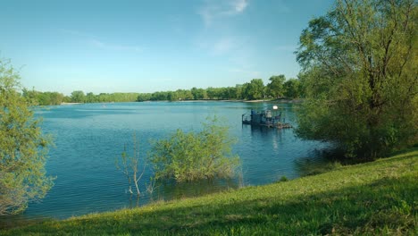 Calm-blue-waters-of-Jarun-Lake-in-Zagreb,-Croatia,-surrounded-by-lush-greenery-under-a-clear-sky