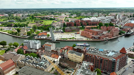 Aerial-view-of-Gdańsk,-showcasing-the-city's-historic-buildings,-modern-Ferris-wheel,-and-the-scenic-Motława-River