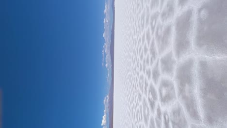 Expansive-white-salt-flats-and-flying-drone-under-a-clear-blue-sky-in-Salinas-Grandes,-Argentina