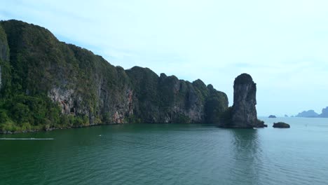 Breathtaking-view-of-a-secluded-bay-with-turquoise-water,-surrounded-by-towering-cliffs-covered-in-lush-green-vegetation