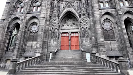 Volcanic-rocks-used-to-build-black-Cathedral-Notre-Dame-of-Assumption-in-Clermont-Ferrand,-the-gothic-facade-with-red-door-and-two-towers,-France