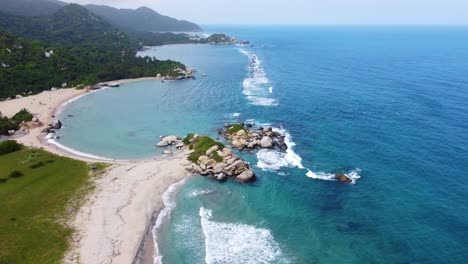 Drone-flying-over-exotic-beach-captures-rocks-and-the-empty-beach-and-tropical-forest