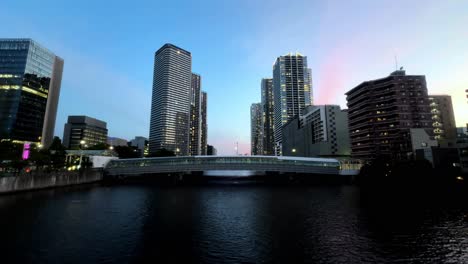 Cityscape-at-twilight-with-high-rise-buildings-and-a-river-bridge,-urban-evening-scene