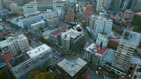 Aerial-reveals-sunshine-above-Santiago-de-Chile,-Providencia-neighborhood-traffic,-Sun's-Pyramid-building