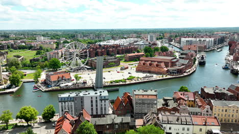 Aerial-of-Gdańsk,-the-city's-historical-architecture,-a-modern-Ferris-wheel,-and-the-scenic-Motława-River