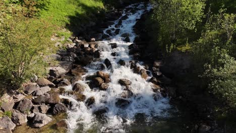 Vibrant-mountain-stream-cascading-over-rocks,-surrounded-by-lush-green-forest