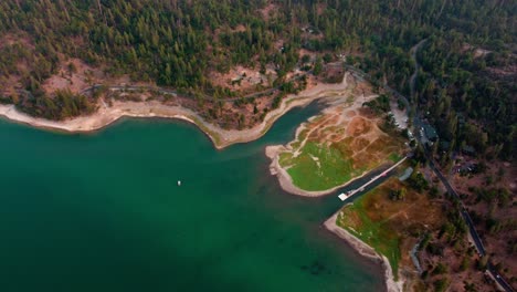 Aerial-Drone-Flyover-Lake-Shore,-Road,-Forests,-And-Cabins-Bass-Lake,-California