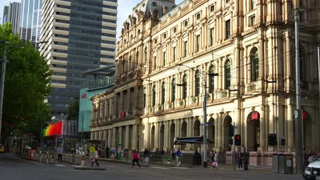 Corner-street-shot-capturing-the-chain-retailer-H-and-M-flagship-store-in-Melbourne's-heritage-listed-GPO-building-with-tram-running-along-Bourke-street-and-pedestrians-waiting-at-Elizabeth-tram-stop